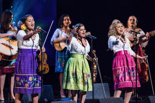 Mariachi Las Colibri singing on stage with 6 elements image of Mariachi Las Colibri on stage singing in colorful dress